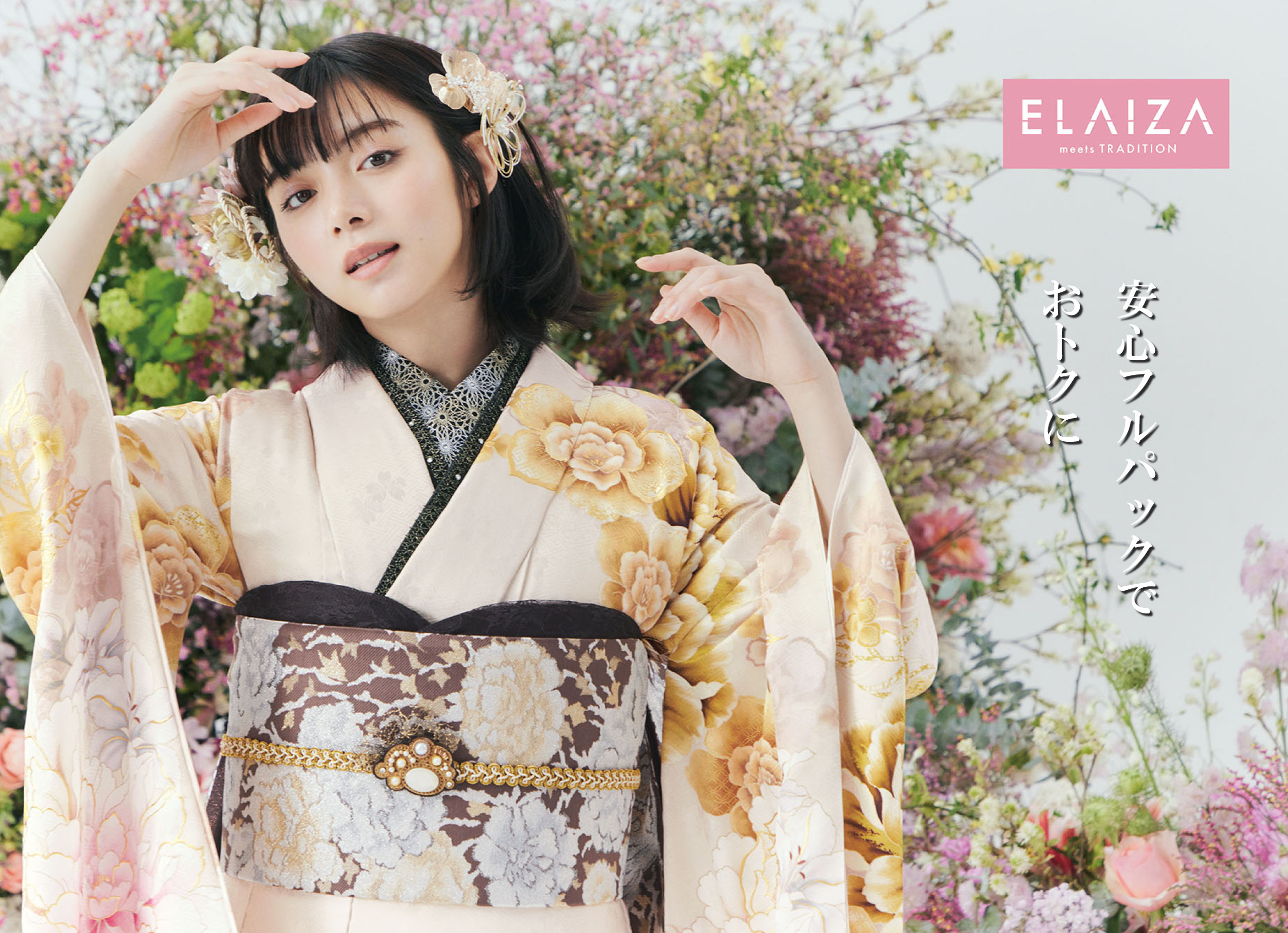 花柄の着物を着た女性が、ピンクと白の花々が豊かに飾られた花の前でポーズをとっています。着物には黄色とピンクの花柄が描かれ、帯は濃い色で対照的です。彼女は顔の近くに手をかざしています。右側には「ELAIZA」のロゴと日本語の文字があります。.