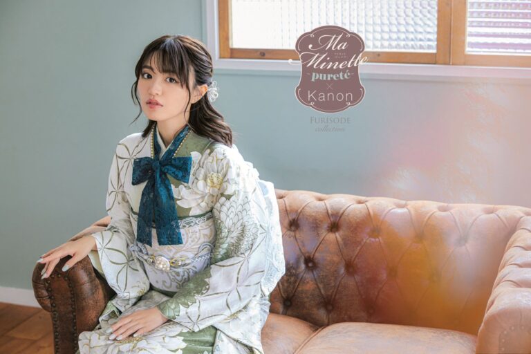 淡い花柄の着物に濃い青緑色の大きなリボンをつけた女性が、茶色の革張りのソファに座っている。髪はヘアピースでセットされており、カメラに向かって優しく見つめている。背景にはすりガラスの窓があり、「Ma Minette pureté x Kanon FURISODE collection」という文字が添えられている。
