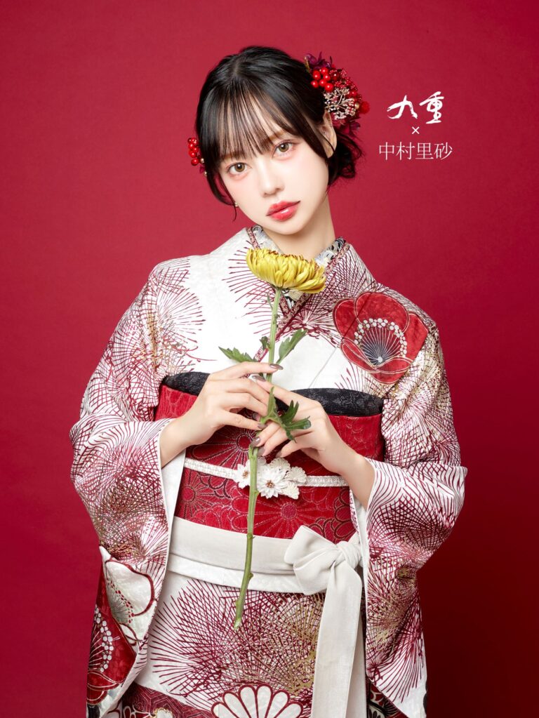 赤と白の模様が入った日本の伝統的な着物を着た女性が赤い背景に立っています。彼女は黄色い花を持ち、赤い花の髪飾りをつけています。右側には日本語の文字があります。彼女の表情は穏やかで、全体的な美観は優雅で穏やかです。.