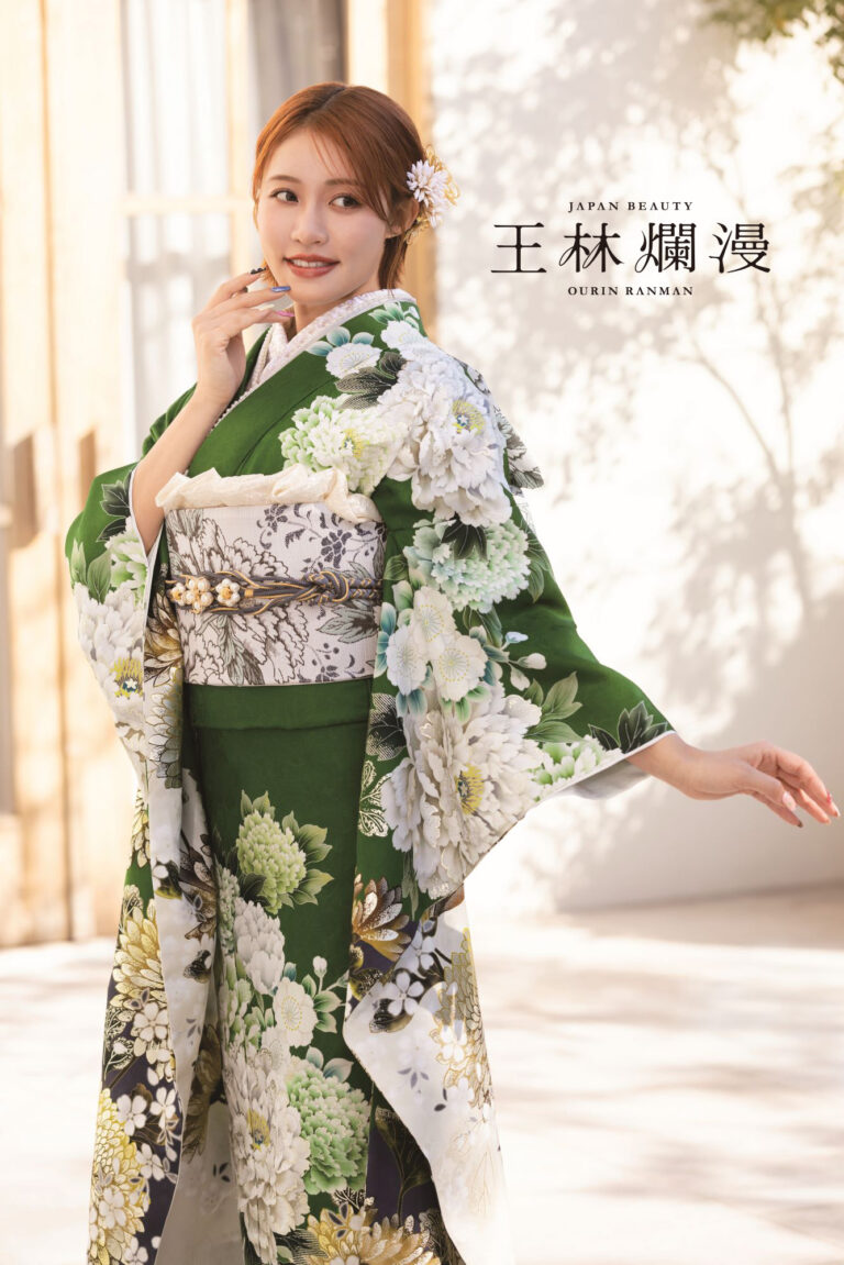 花柄の緑と白の着物を着た女性が屋外でポーズをとっています。彼女の茶色の髪は白い花で飾られています。太陽の光が彼女の後ろの壁に柔らかな影を落としています。上部には「Japan Beauty」と「OULIN RANMAN」の文字があります。.