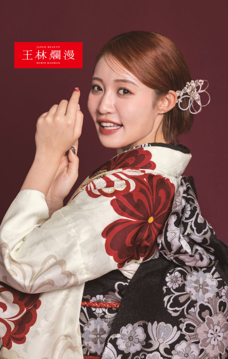 赤い花柄の白と黒の着物を着た女性が、濃い赤の背景に微笑んでいます。彼女の髪は、装飾的なヘアピースでエレガントにスタイリングされています。彼女は、赤いマニキュアを見せながら、顔の近くに手をかざしています。左上隅に赤と白のロゴがあります。.