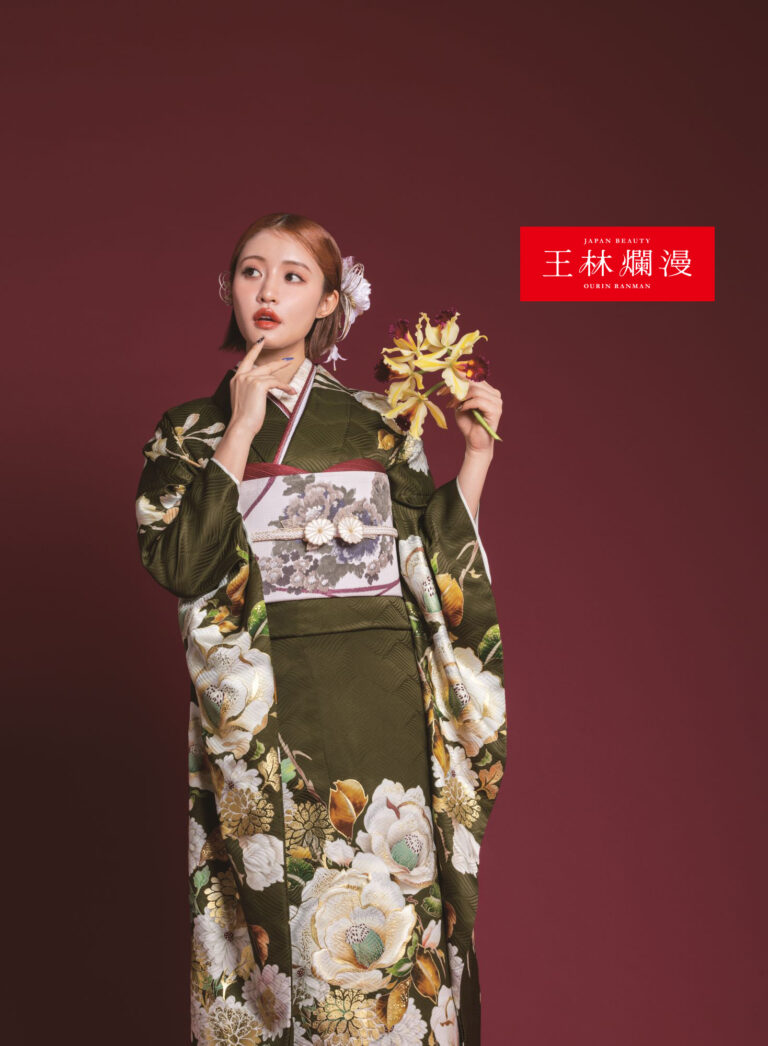 緑の花柄の着物を着た女性が、栗色の背景に黄色の花束を持って立っています。髪には白い花を挿し、物思いにふける表情をしています。着物には大きくて華やかな花が描かれており、右上には赤い日本語の文字で文章が書かれています。.