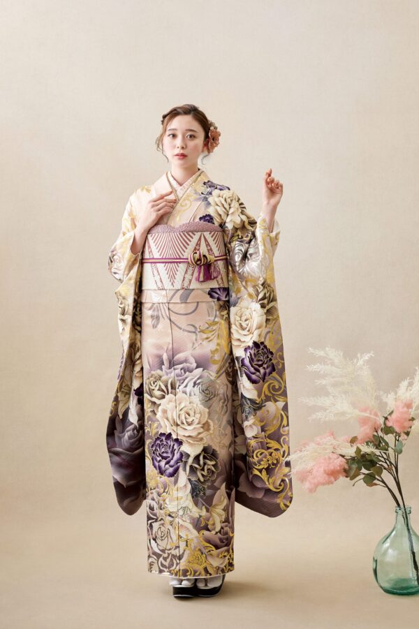 ベージュの背景に、金、紫、クリーム色の花柄があしらわれた着物4053（複製）を着た女性がポーズをとっている。髪には花を挿し、袖を持ち、傍らにはピンクと白の花が入ったガラスの花瓶が置かれている。.